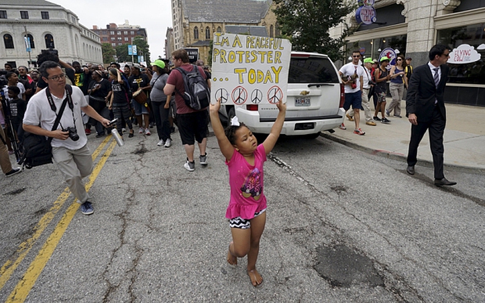 Một bé gái giơ cao tấm biển biểu tình. Ảnh: Reuters