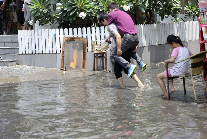 Hai thanh niên cõng nhau qua dòng nước ngập