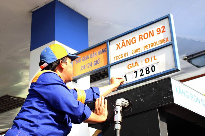 Nhân viên một cây xăng tại TP HCM đang niêm yết giá bán mới vào chiều 11-3 Ảnh: HOÀNG TRIỀU