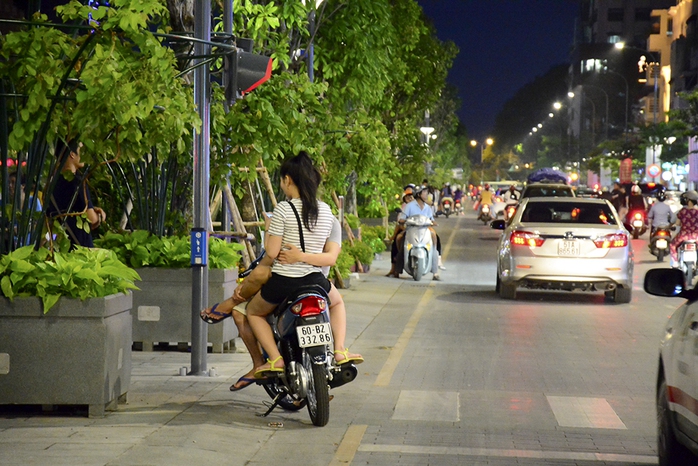 Một cặp đôi hẹn hò ngay dưới lòng đường trên phố đi bộ Nguyễn Huệ, bất chấp dòng xe cộ qua lại đông đúc.  - Ảnh: Thăng Bình