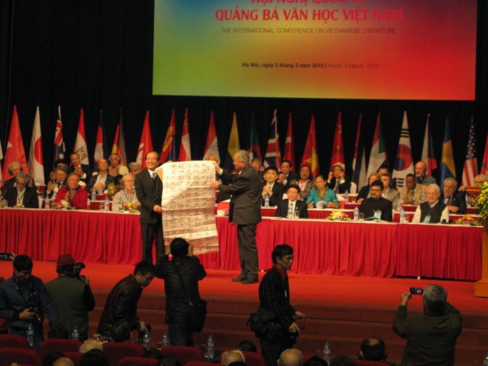Dịch giả Chúc Ngưỡng Tu (phải, giữa ảnh) tặng nhà thơ Hữu Thỉnh bài thơ của Chủ tịch Hồ Chí Minh do ông chuyển ngữ tại Hội nghị quảng bá văn học Việt Nam ra thế giới lần thứ 3 Ảnh: LÊ NAM