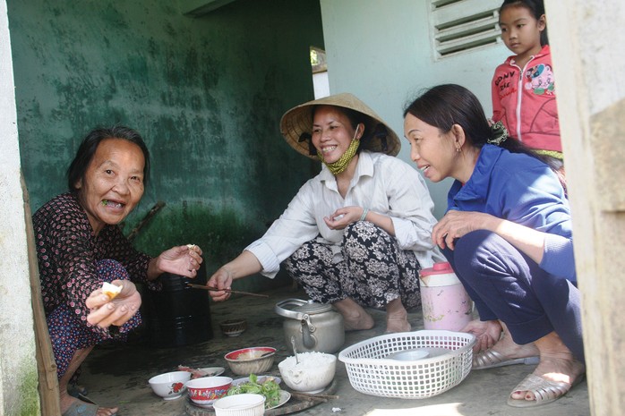 Bà Phạm Thị Sòng (bìa trái) dùng bữa cơm trưa do nhà bà Bùi Thị Thu Tuyết nấu dọn
