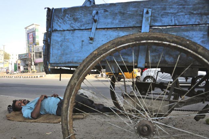 Nằm ngủ dưới bóng râm ngoài đường ở Hyderabad. Ảnh: AP