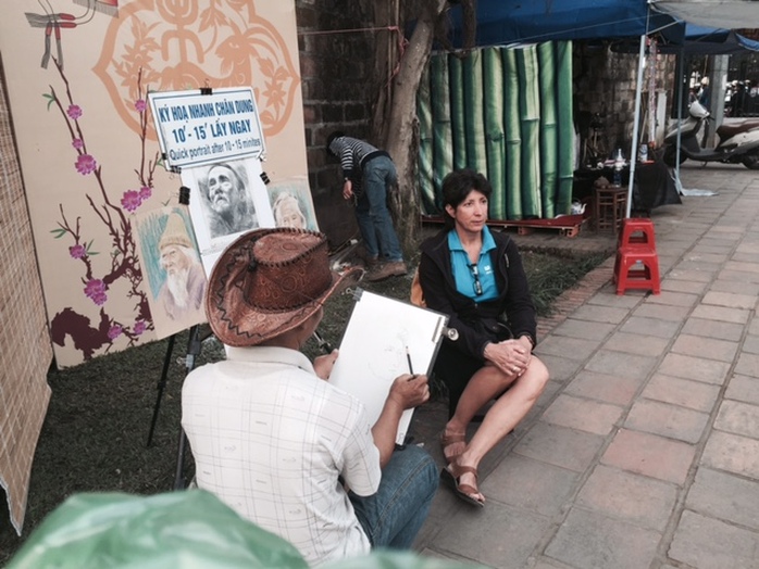 Một du khách nước ngoài thích thú với việc vẽ ký họa chân dung trong Hội chữ Xuân Ất Mùi.