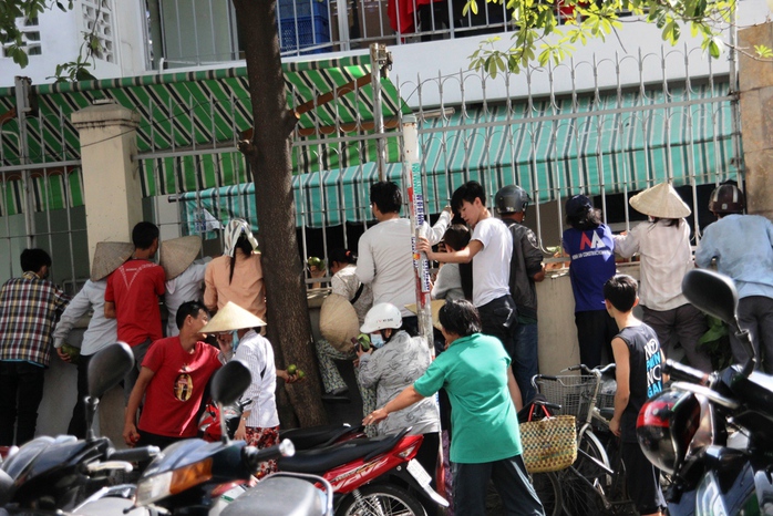 Chiều 29-8, một công ty may trên địa bàn quận Phú Nhuận tổ chức cúng cô hồn. Phía ngoài hàng chục người đu hàng rào đợt nhận tiền, đồ cúng.