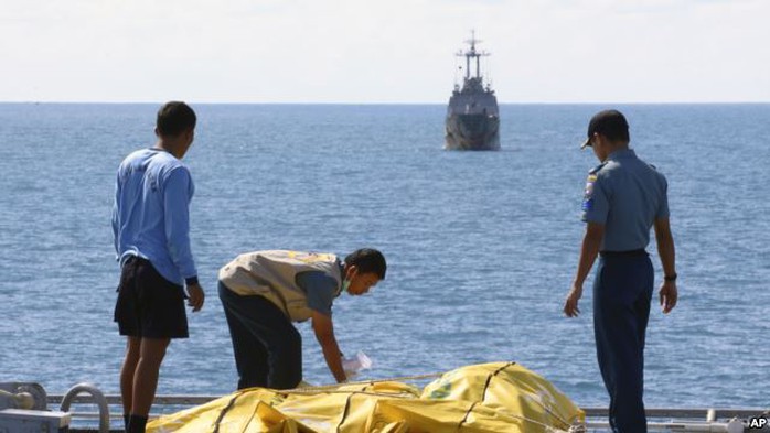 Crew members inspect bags containing bodies believed to be victims of AirAsia Flight 8501 on the deck of Indonesian Navy ship KRI Banda Aceh, on the Java Sea, Indonesia, Friday, Jan. 23, 2015.