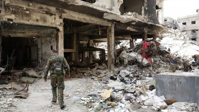 A Palestinian fighter walks through the rubble of the Yarmouk camp