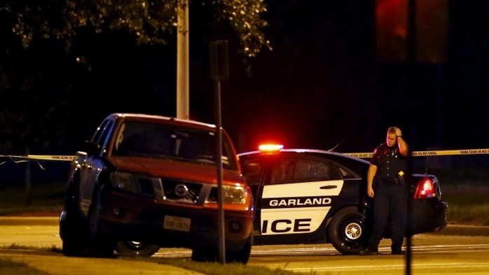 A police officer stands near the suspects vehicle after a shooting outside the Muhammad Art Exhibit and Contest on Sunday.