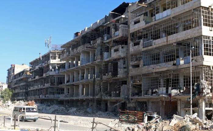 A bus drives past damaged buildings along a street in Aleppos al-Shaar neighborhood, Syria July 13, 2015. REUTERS/Abdalrhman Ismail