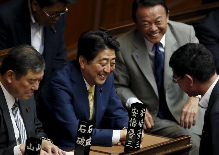 Japans Prime Minister Shinzo Abe (C) smiles with Finance Minister and Deputy Prime Minister Taro Aso (2nd R) and other lawmakers before the lower house plenary session at the parliament in Tokyo July 16, 2015. REUTERS/Toru Hanai