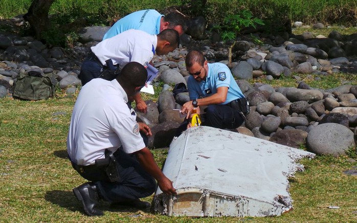 French gendarmes and police inspect a large piece of plane debris which was found on the beach in Saint-Andre, on the French Indian Ocean island of La Reunion, July 29, 2015. Frances BEA air crash investigation agency said it was examining the debris,  in coordination with Malaysian and Australian authorities, to determine whether it came from Malaysia Airlines Flight MH370, which vanished last year in one of the biggest mysteries in aviation history. Picture taken July 29, 2015.     REUTERS/Zinfos974/Prisca Bigot      TPX IMAGES OF THE DAY      - RTX1MCP2