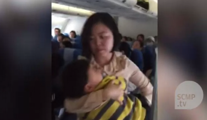 Người phụ nữ bế con trai 3 tuổi khỏi máy bay. Ảnh: SCMP