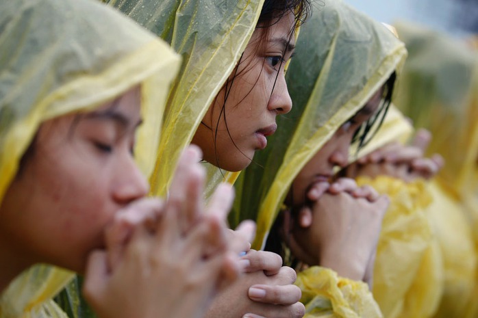 Các tín đồ cầu nguyện dưới mưa. Ảnh: ABS-CBN