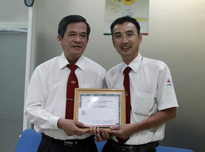 Ông Huỳnh Văn Sĩ, Phó Tổng giám đốc Vinasun, trao giấy khen và tiền thưởng cho lái xe Phạm Đình Hưởng