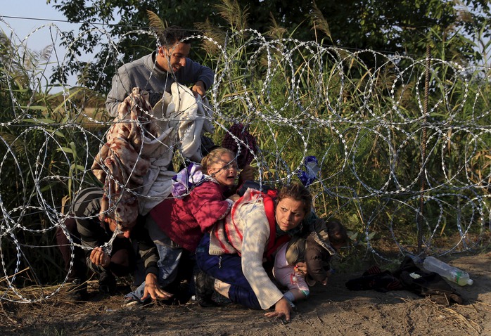 Người di cư Syria ở Serbia vượt qua hàng rào dây thép gai để vào Hungary hôm 27-8Ảnh: Reuters