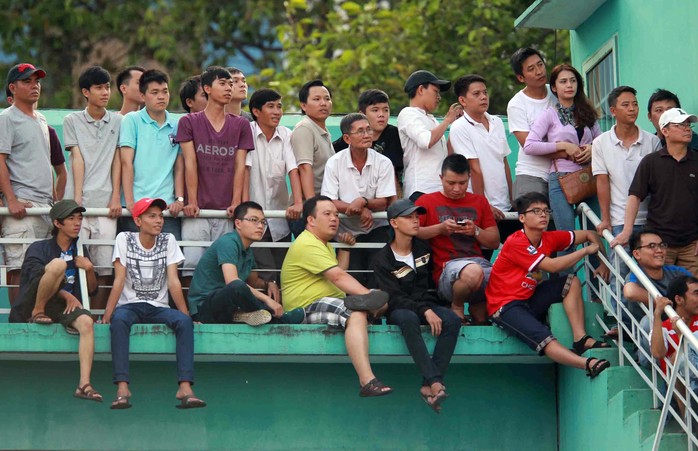 Thiếu chỗ ngồi nên nhiều người leo qua lan can theo dõi 
trận đấuẢnh: Quang Liêm