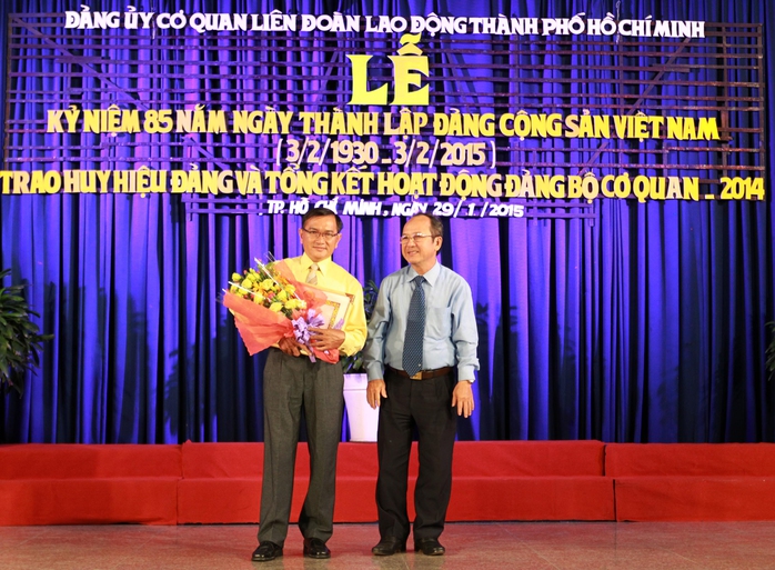 Ông Nguyễn Hoàng Năng (bìa phải), Bí thư Đảng ủy Khối Dân - Chính - Đảng, trao huy hiệu 30 năm tuổi Đảng cho đảng viên Võ Văn Tấn, Chi bộ Trường Trung cấp Công đoàn TP