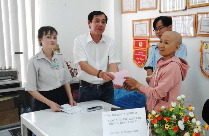 Đại diện Công đoàn Công ty TNHH D.I trao tiền hỗ trợ cho chị Thủy (bìa phải)