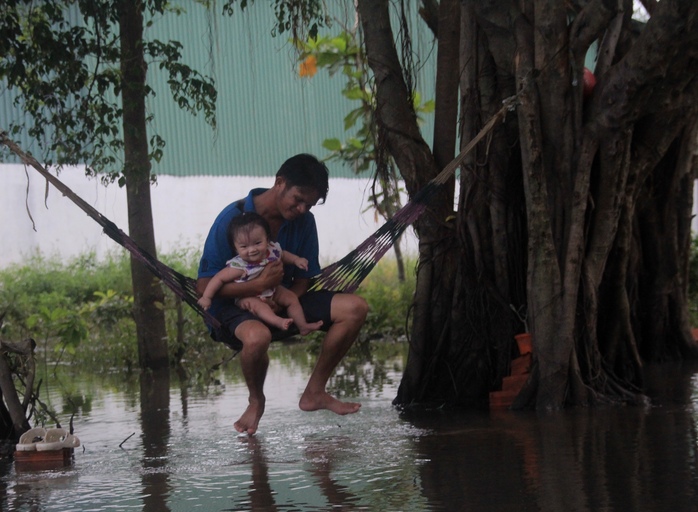 Hai cậu cháu phải mắc võng vui chơi trên dòng nước ngập