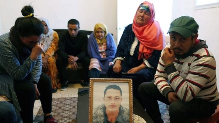 Gia đình Anis bên ngồi quanh bức chân dung của hắn tại Tunisia. Ảnh: EPA