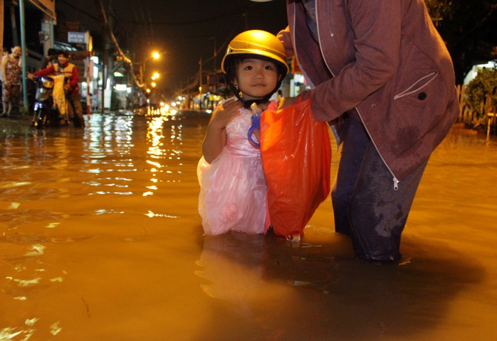 Một bé gái lội nước trên đường Lê Văn Lương.