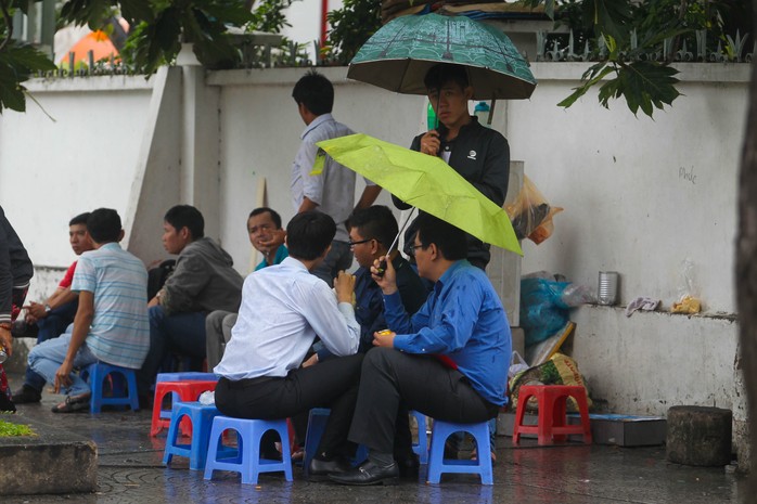 
Vừa che dù vừa uống cà phê vỉa hè trong ngày áp thấp
