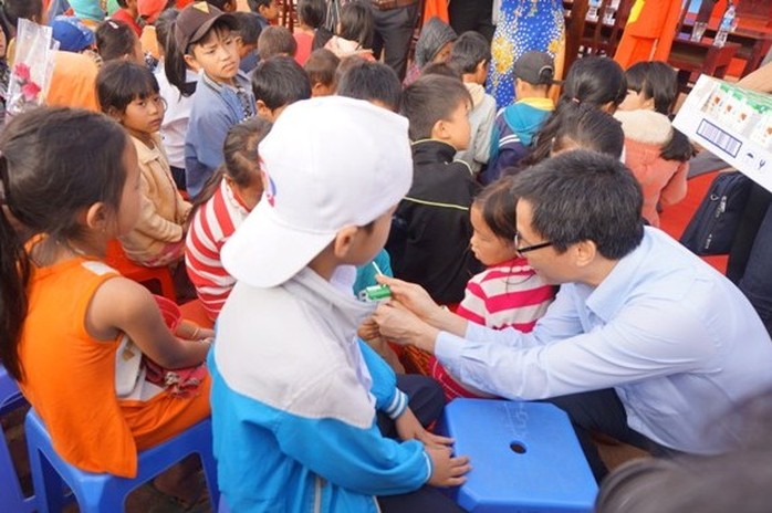 
Phó Thủ tướng ân cần phát sữa cho các em học sinh. Ảnh B.N
