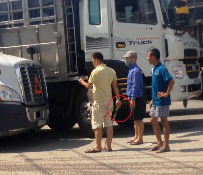 
Tài xế xe tải (áo vàng) cầm thanh sắt đe dọa tài xế xe container
