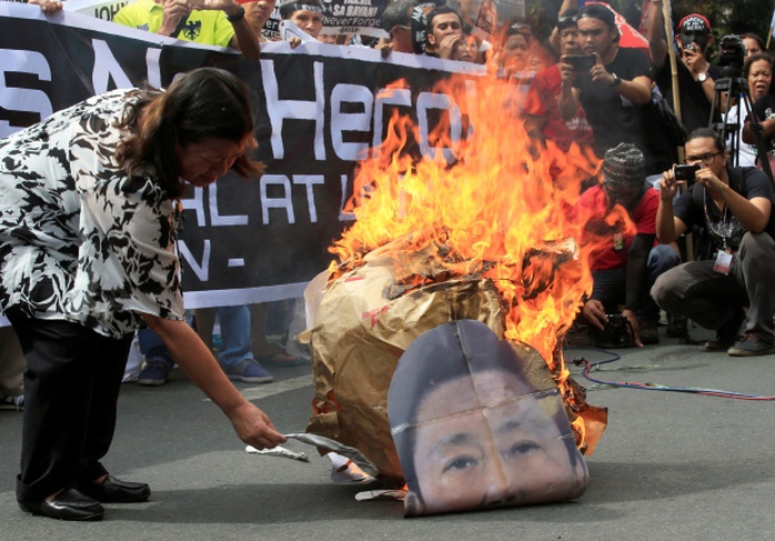 
Một người biểu tình đốt hình ông Marcos. Ảnh: Reuters

