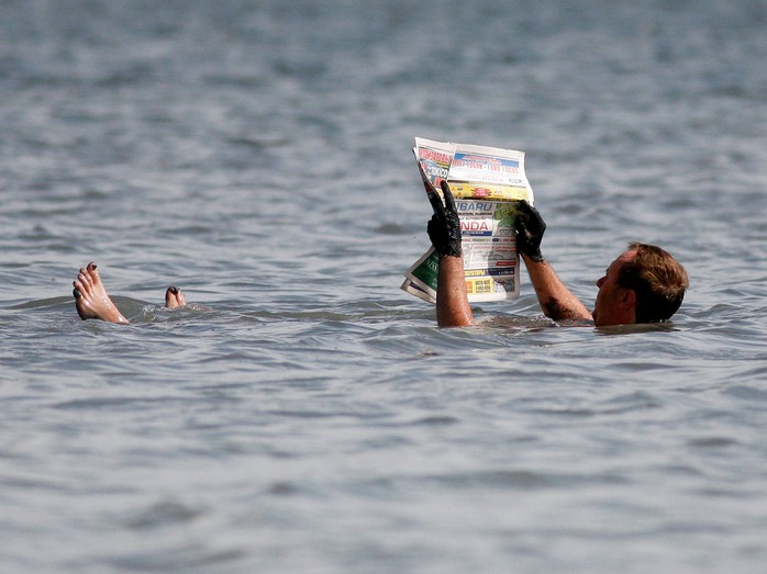 Người đàn ông đọc báo giữa hồ nước mặn Tus ở vùng Khakassia vủa Nga. Ảnh: Reuters