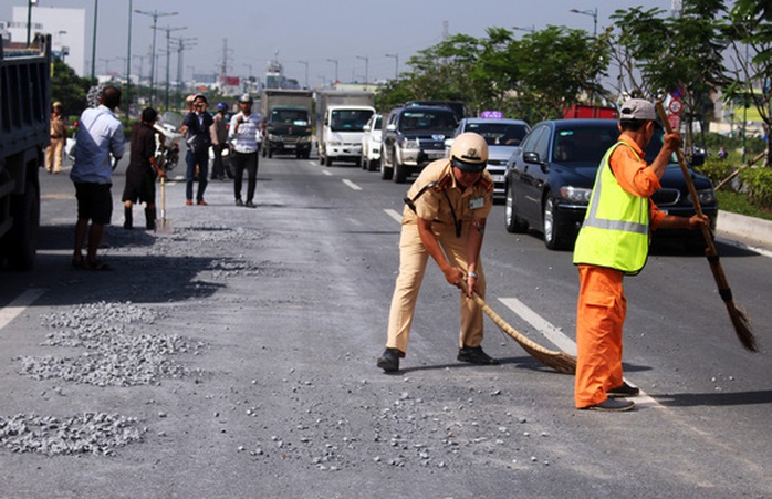 
Lực lượng CSGT phụ công nhân vệ sinh dọn dẹp đá dăm rơi vãi trên đường Phạm Văn Đồng.
