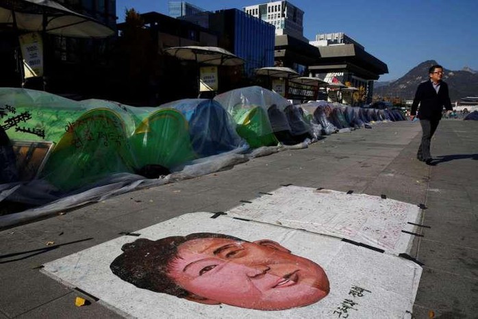 
Bức tranh vẽ Tổng thống Park trên đất trước lều trại của những người xuống đường đòi bà từ chức. Ảnh: REUTERS, EPA
