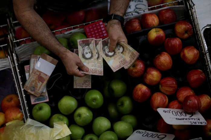 Tiền 100 bolivar được tiêu thụ ở chợ tại thủ đô Caracas. Ảnh: REUTERS