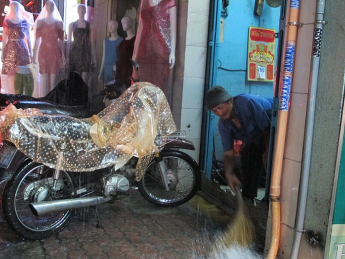 
Một người sống trên đường Nguyễn Thị Minh Khai quét nước tràn vào hiên nhà
