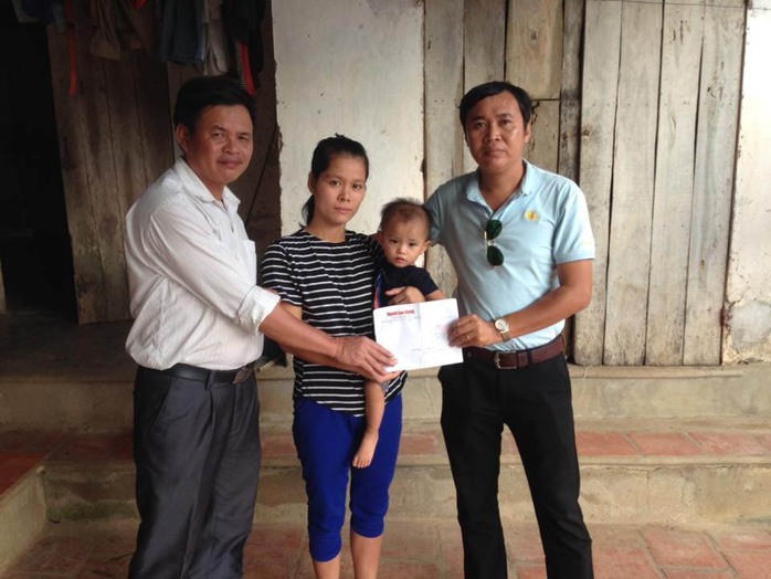 Gia đình bé Nguyễn Cảnh Chính nhận tiền hỗ trợ từ Quỹ Regina do phóng viên Báo Người Lao Động (bìa phải) đến traoẢnh: HẢI VŨ