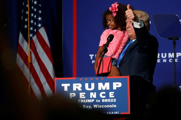 
Ông Donald Trump bế 1 đứa trẻ trên khán đài ở Green Bay, bang Wisconsin đêm 17-10 Ảnh: REUTERS
