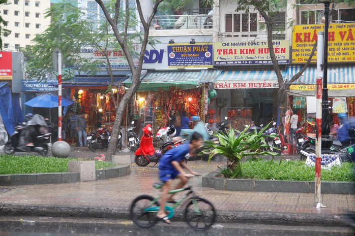 
Nhiều cửa tiệm buôn bán hàng hóa ngày Tết phải tất tả dọn đồ khi mưa đổ xuống (Ảnh: H.P)
