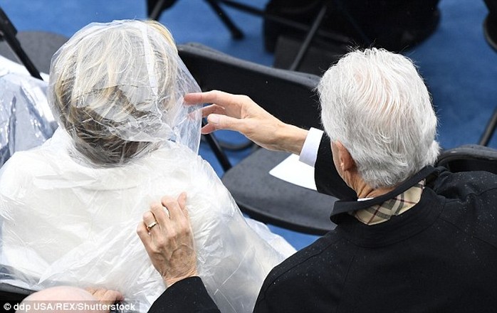 
Ông Clinton chỉnh áo mưa cho vợ. Ảnh: Rex
