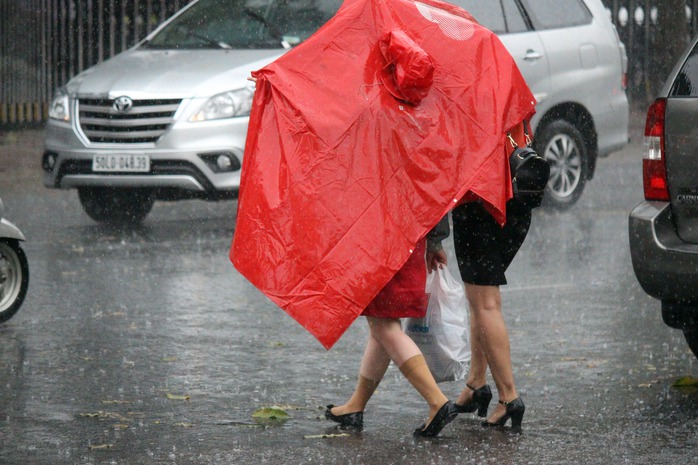 
Khi mưa nhẹ hạt đi, nhiều người che chung áo mưa để về.
