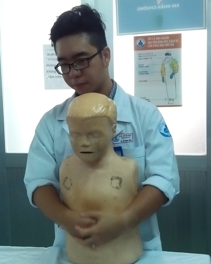 Bác sĩ Bệnh viện Nhi Đồng 1 chỉ cách ôm trẻ từ phía sau, xốc và ấn mạnh để tống dị vật ra ngoài - ảnh KIM THÙY
