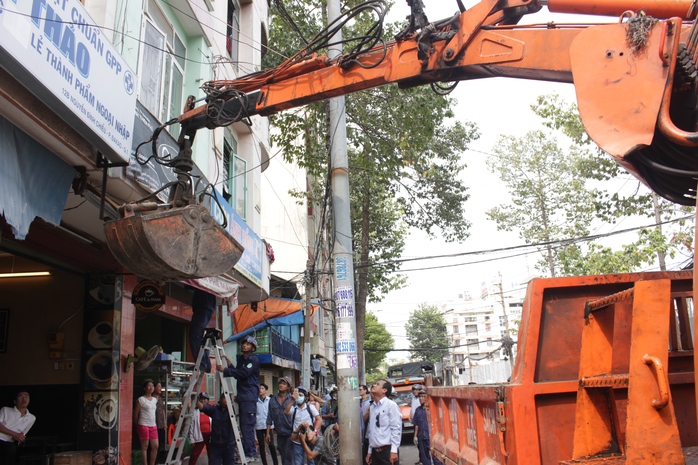 
Tại đường Nguyễn Bỉnh Khiêm, thấy nhiều hàng quán lấn chiếm vỉa hè, ông Hải chỉ đạo tịch thu đồ đạc, dùng máy kéo tháo gỡ các mái che, trả lại vỉa hè thông thoáng.
