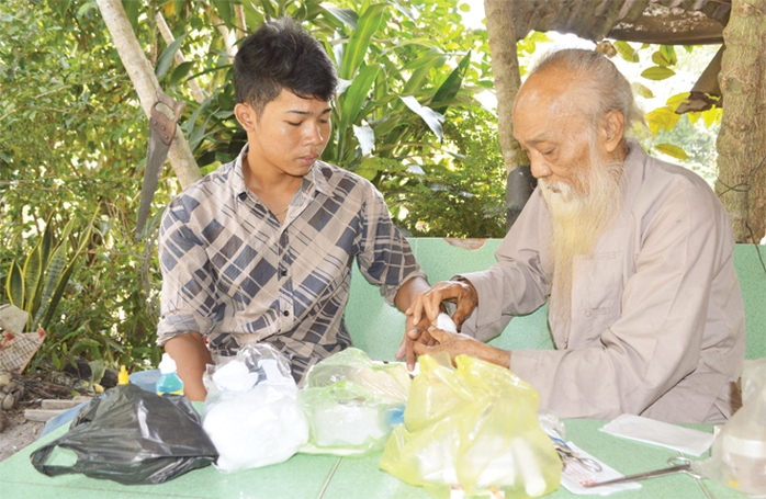 
Ông Tư Đền bó thuốc cho anh Chau Rit
