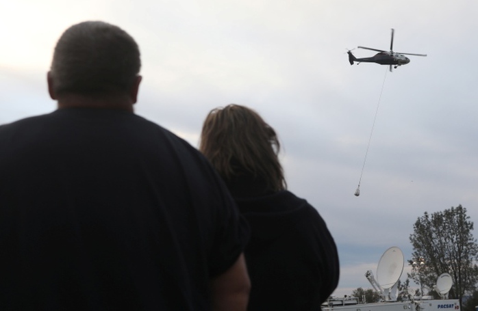 Các nhà chức trách dùng trực thăng lấp lỗ trên đập.Ảnh: REUTERS