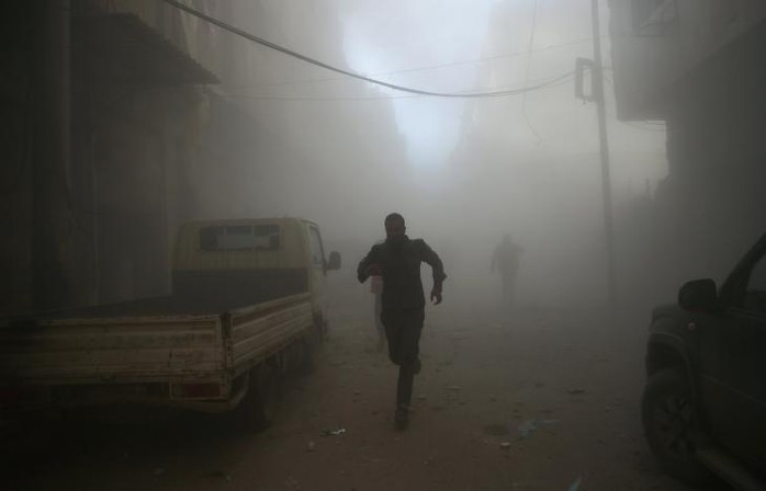 Một người chạy khỏi khu vực bị đánh bom ở thị trấn Douma, gần thủ đô Damascus, vào ngày 19-2. Ảnh: REUTERS