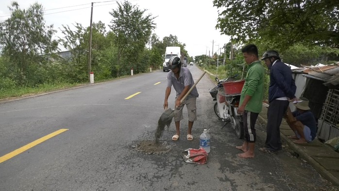 Một số người dân địa phương phụ ông Trần Phước Hoàng vá đường Một số người dân địa phương phụ ông Trần Phước Hoàng vá đường