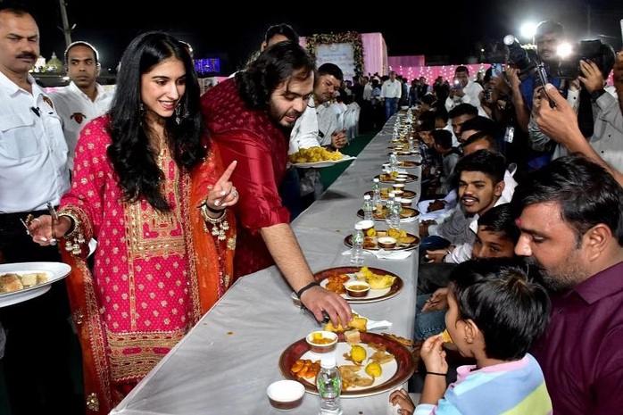 Anant Ambani và vợ sắp cưới phục vụ món ăn truyền thống cho dân làng. Ảnh: Reuters Anant Ambani và vợ sắp cưới phục vụ món ăn truyền thống cho dân làng. Ảnh: Reuters
