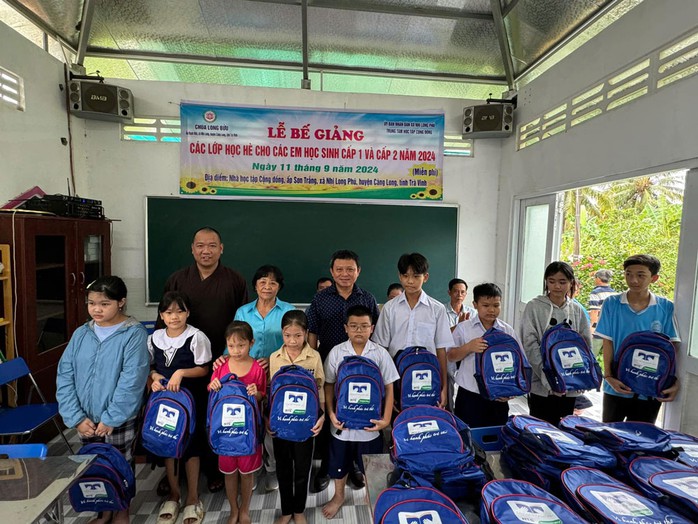 Đại đức Minh Trí và các nhà hảo tâm tặng cặp sách mới cho học sinh tại lớp học hè. (Ảnh do nhân vật cung cấp) Đại đức Minh Trí và các nhà hảo tâm tặng cặp sách mới cho học sinh tại lớp học hè. (Ảnh do nhân vật cung cấp)