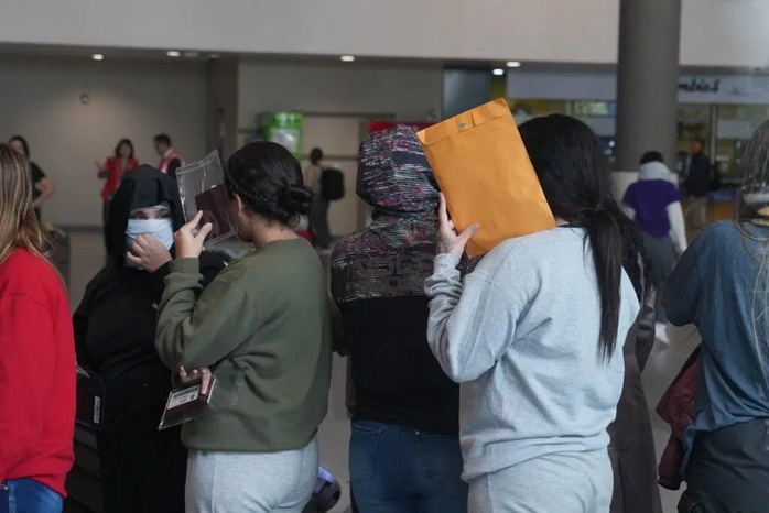 A group of female migrants hide their faces as they wait to pick up their bags at one of the luggage carrousels at Bogota’s airpot. They were deported on a flight run by a US contractors. Manuel Rueda/The World A group of female migrants hide their faces as they wait to pick up their bags at one of the luggage carrousels at Bogota’s airpot. They were deported on a flight run by a US contractors. Manuel Rueda/The World