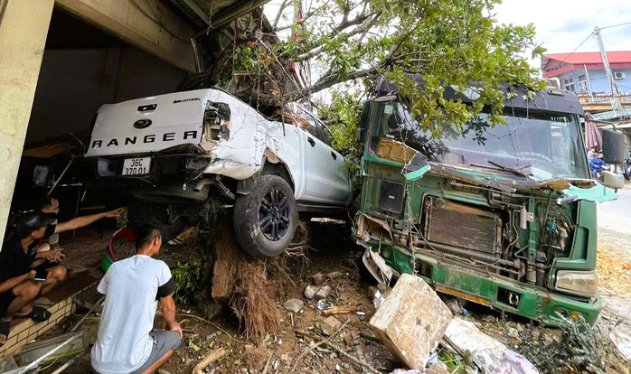 Xe tải mất lái tông trúng ô tô đậu bên đường, bật gốc cây lộc vừng - Ảnh 1.