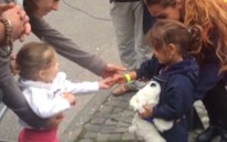 Bé gái người Đức chia kẹo cho em bé tị nạn
